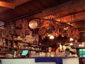 a photo of the beautiful bar of Theo's with dry flowers hanging above the entire bar